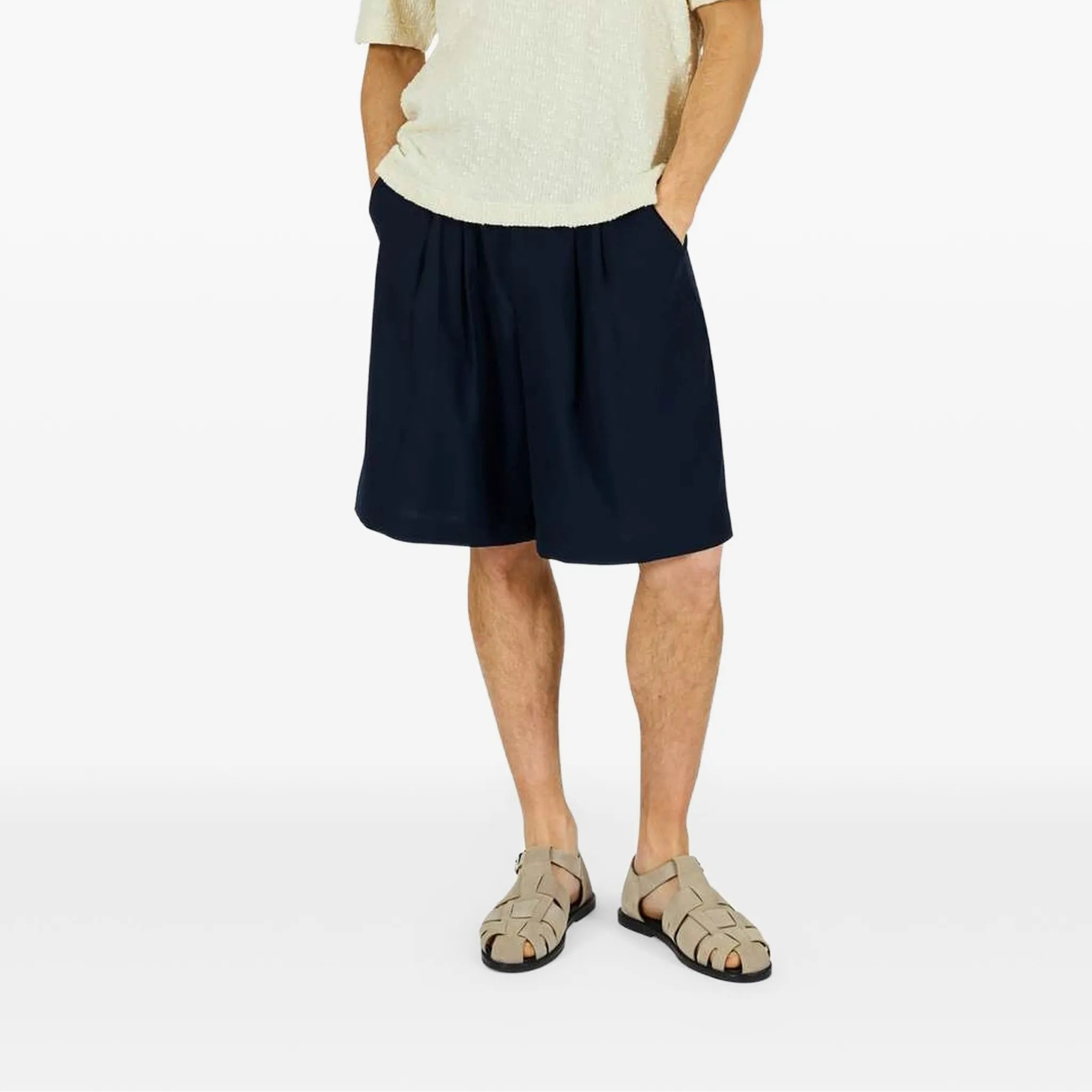 Person wearing a beige polo shirt and navy shorts on a white background