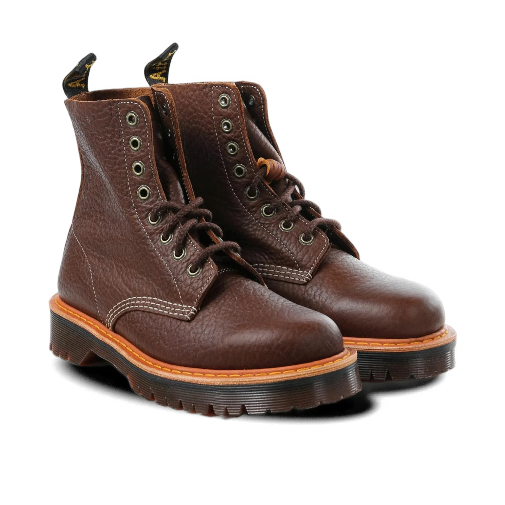 Pair of brown leather boots with orange soles on a white background