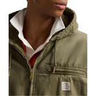 Close-up of a person wearing an olive green hooded jacket with a white collared shirt underneath, shown against a plain white background.