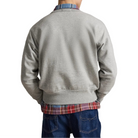 Back view of a model in the heather gray sweatshirt. A plaid shirt shows at the collar and hem, and he’s wearing dark jeans.