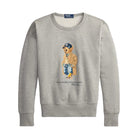 Heather gray crewneck sweatshirt laid flat. On the front is a graphic of a bear wearing a navy NY cap, a tan coat and jeans, with “Polo Bear by Ralph Lauren” printed below.