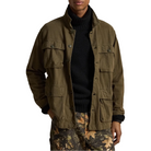 A man wearing an olive green military-style field jacket over a black turtleneck sweater and camouflage pants, shown from the waist up against a plain white background.