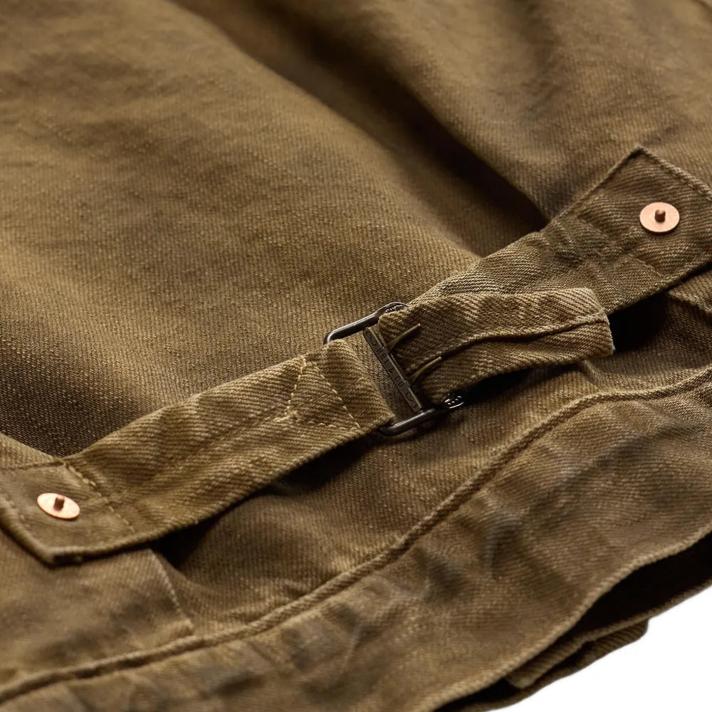 Close-up of an olive brown canvas jacket with a strap closure and brass snap buttons, set against a plain white background.