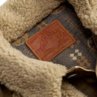 Close-up of a beige sherpa fleece collar and lining of a vintage work jacket, showing a brown leather patch with 'Overalls Double RL Co.' branding.