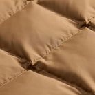 Close-up of a quilted puffer jacket in a warm tan or camel brown color, showing the stitched diamond compartments and smooth fabric texture.