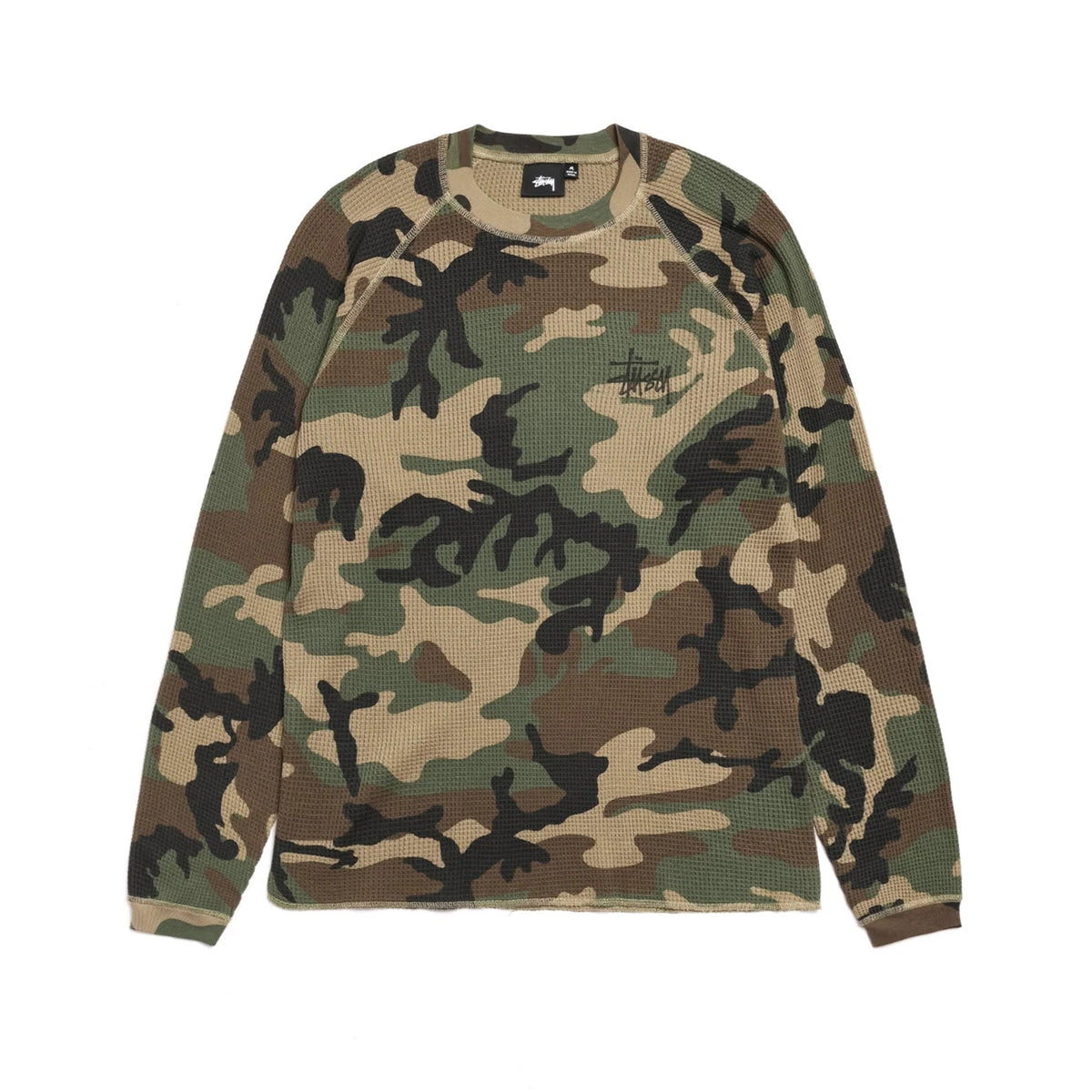 Front view of the Stüssy Basic Stüssy Thermal in woodland camo laid flat. A long-sleeve waffle-knit top in olive, tan, brown and black camo with raglan sleeves and a small black Stüssy logo on the chest.