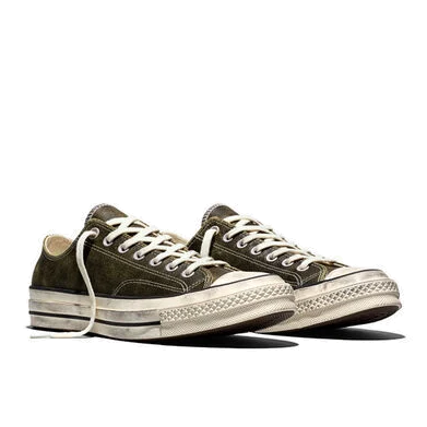 Pair of moss-green Converse Chuck 70 Burnished Leather low-tops at a front three-quarter angle, showing the worn rubber toe caps and distressed midsoles.