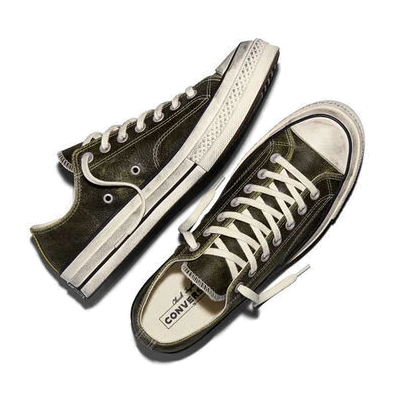 Top-down view of a pair of moss-green Converse Chuck 70 Burnished Leather low-tops, one on its side, showing the cream laces and the Chuck Taylor logo on the insole.