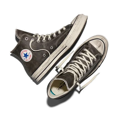 Top-down view of a pair of black Converse Chuck 70 Hi Burnished Leather sneakers, one on its side with the ankle patch showing, and the Converse logo on the insole.