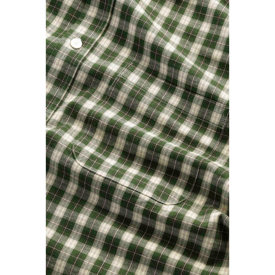 Close-up of the green and cream check fabric, showing a white button and the chest pocket.