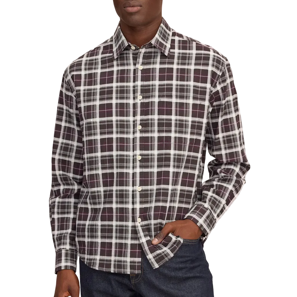 A man wearing a long-sleeve button-down plaid shirt in dark purple , white, and gray, paired with dark blue jeans, standing against a whitee background.