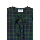 Close-up of the V-neck on The Tiny Big Sister Green Check Bow Blouse, showing the self-fabric bow, navy buttons and brand label.
