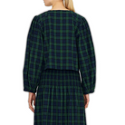 Back view of a model wearing The Tiny Big Sister Green Check Bow Blouse with a matching smocked maxi skirt, showing the cropped length and balloon sleeves.