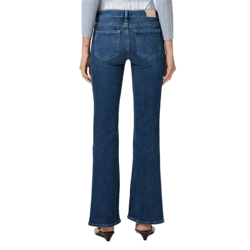 A person shown from the back wearing dark blue flare jeans, a light gray long-sleeve top, and black pointed-toe heels against a plain white background.