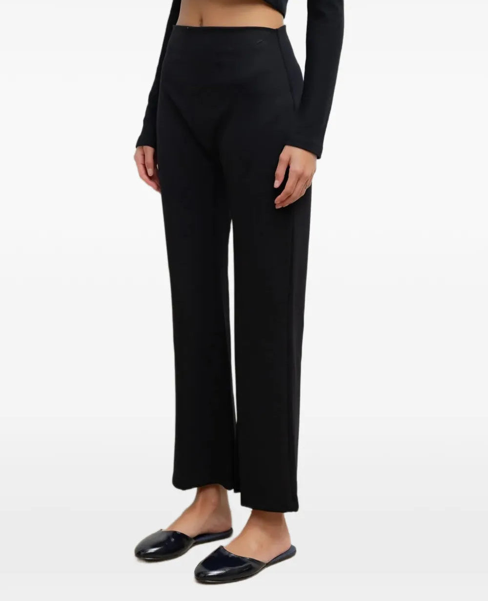 A model wearing black wide-leg cropped trousers with a high waist, paired with black flat loafers, shown against a plain white studio background.