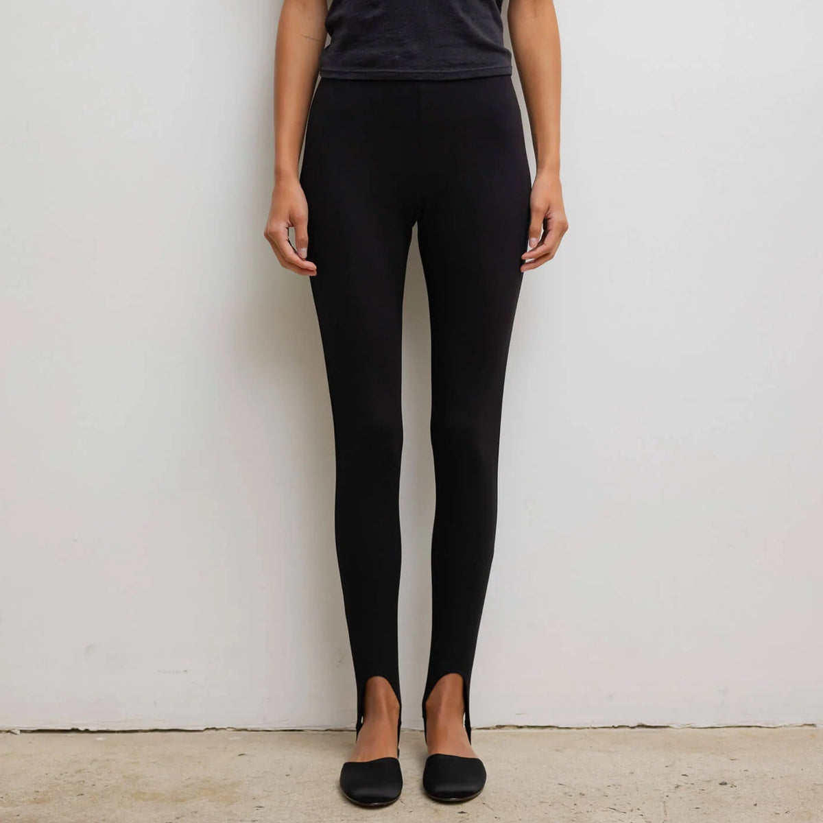 Person wearing a black t-shirt and black leggings against a white background