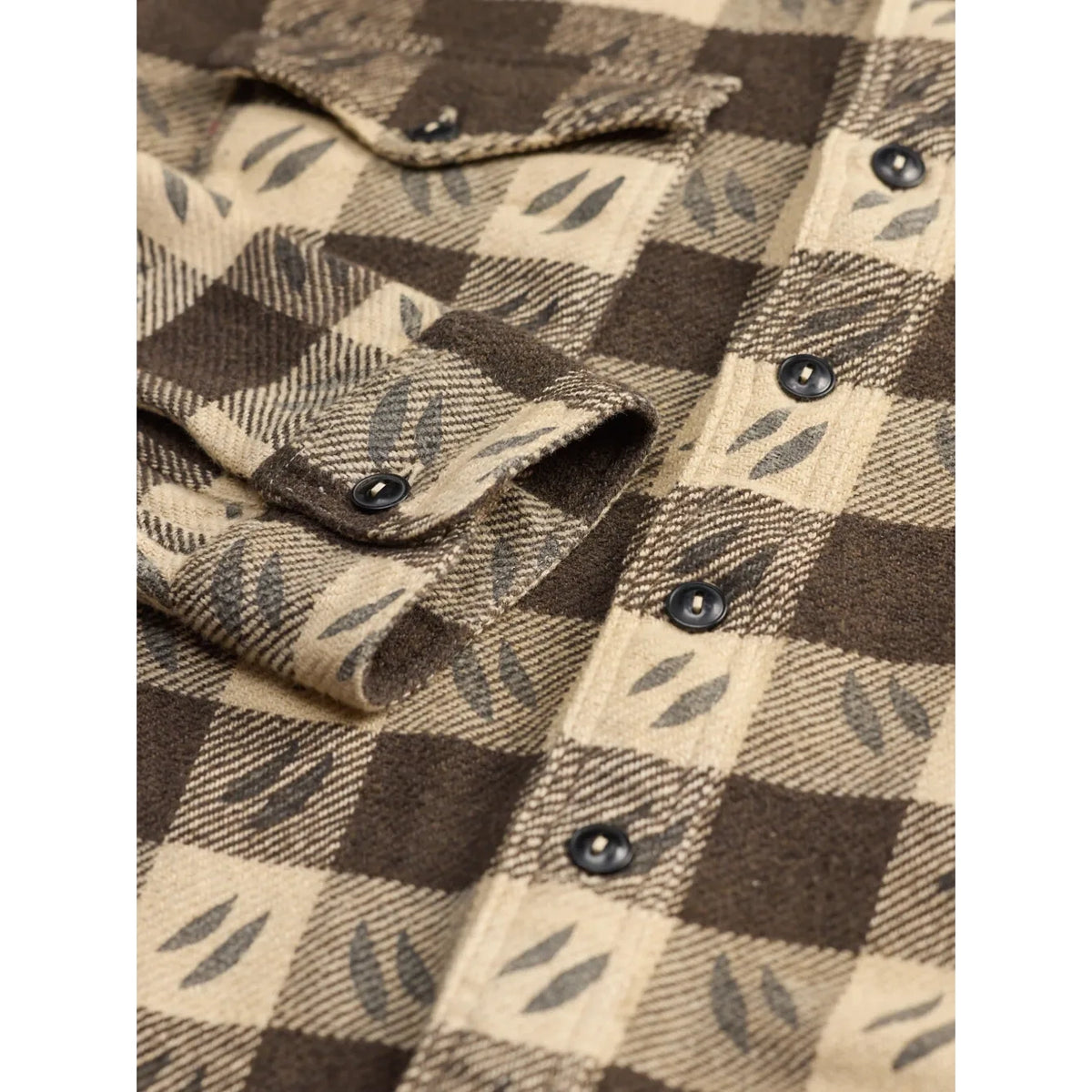 Close-up of a brown and beige plaid button-up shirt with a leaf pattern, showing the fabric texture and snap buttons.