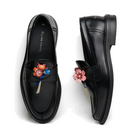 Pair of black Filling Pieces Loafer Bouquet shoes on white, one from above and one on its side, each with a colorful leather flower bouquet pinned to the penny strap.