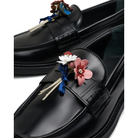 Close-up of the hand-made leather bouquet on a black Filling Pieces loafer, with pink, red, and white leather flowers tied with a blue satin ribbon.