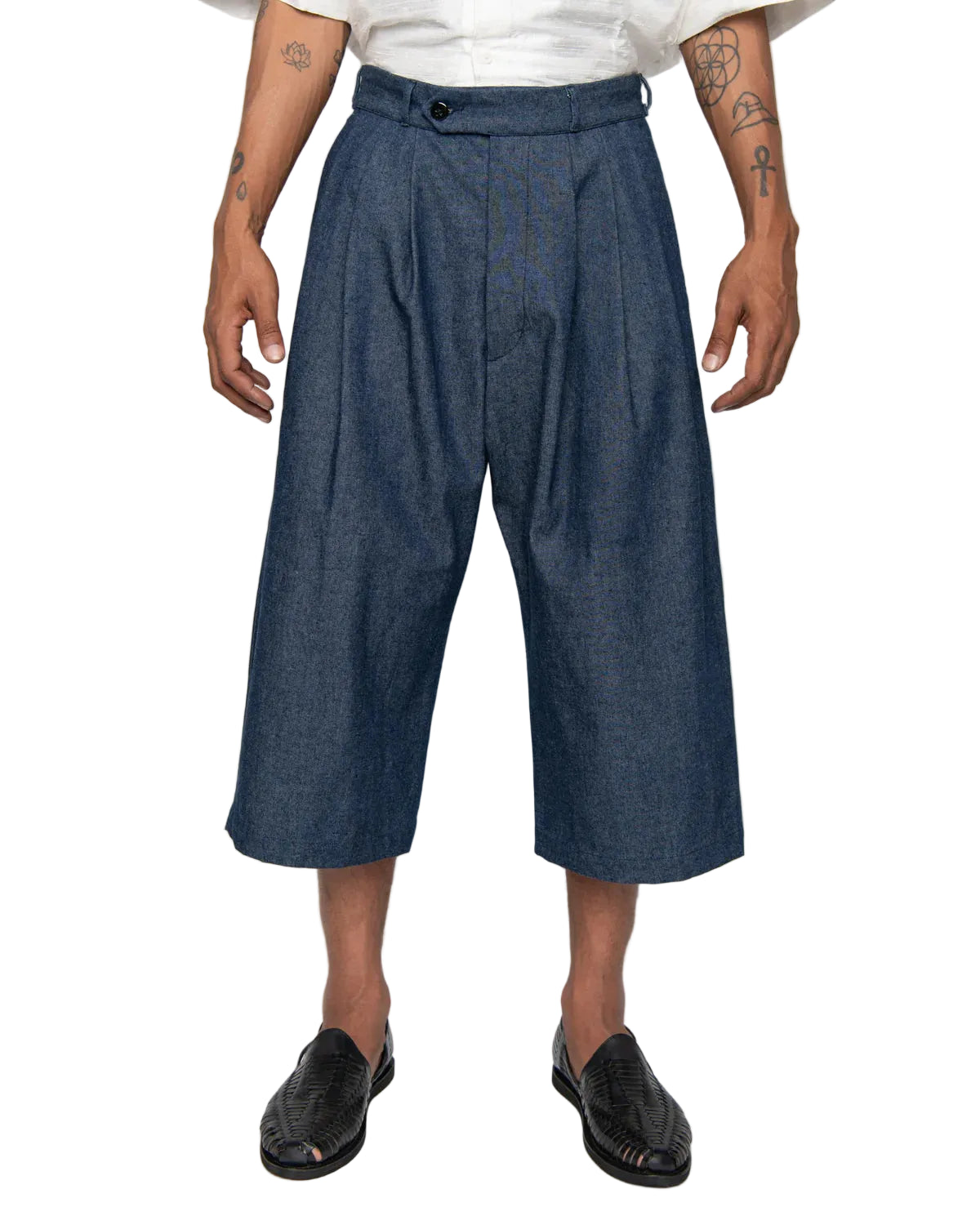 Person wearing blue pleated cropped pants on a white background