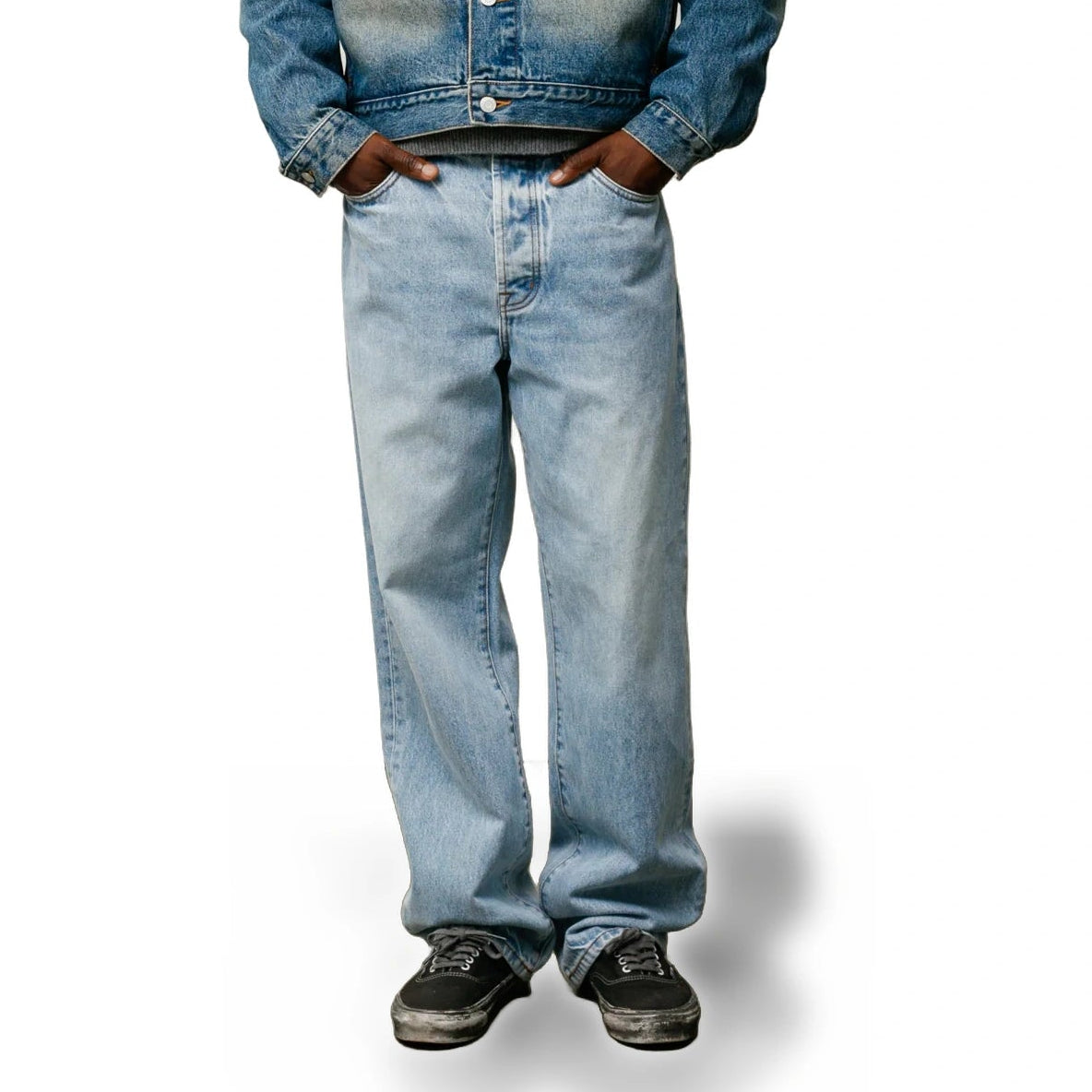 A model wears the light wash New Classic Jean with a medium-wash denim jacket over a gray sweater and black canvas sneakers.