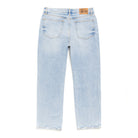 Back view of the light wash New Classic Jean laid flat, showing the two back pockets and a Stüssy leather-look patch at the waistband.
