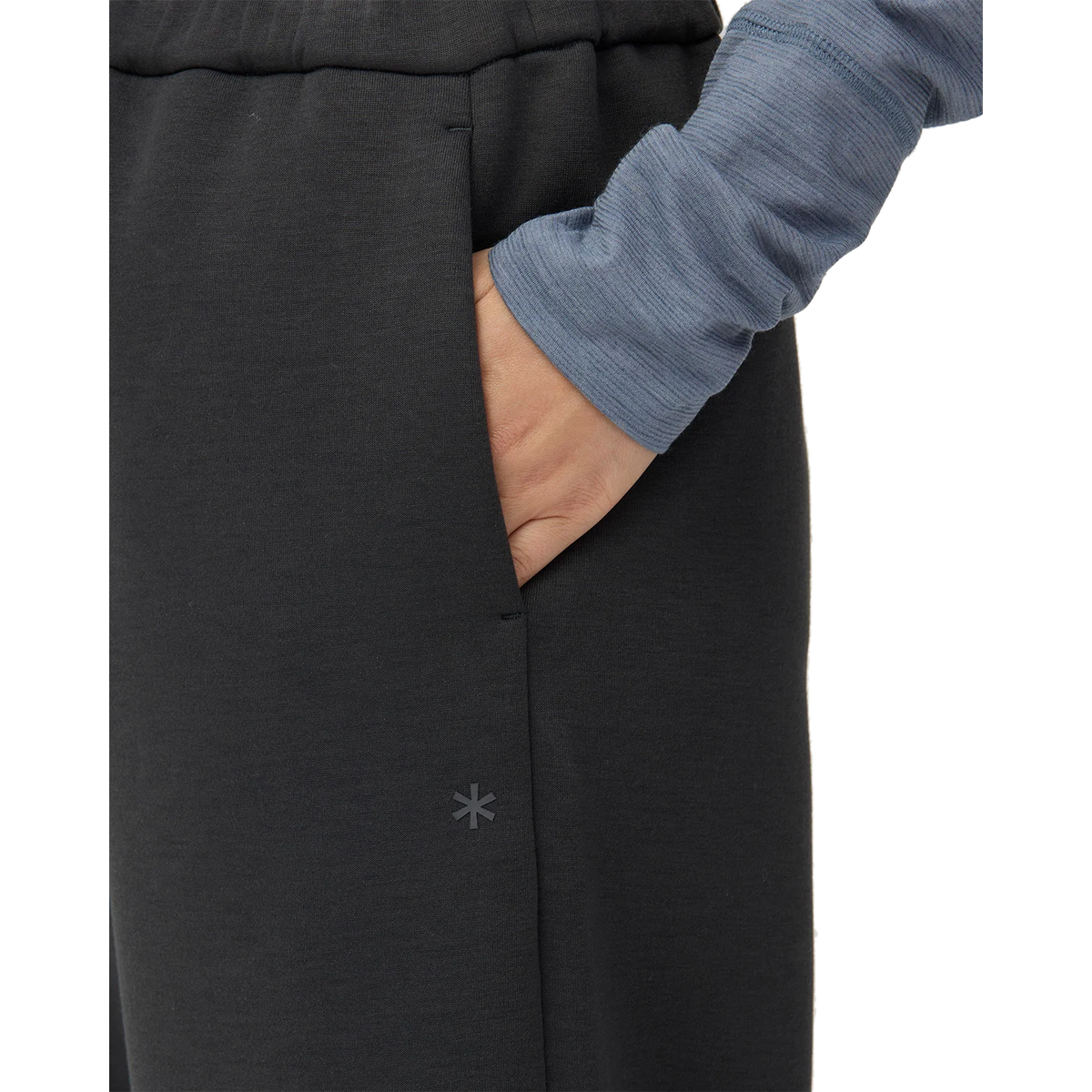 Close-up of a hand in the side pocket of charcoal Snow Peak Odor Control Women’s Pants, with the small Snow Peak logo printed on the hip.