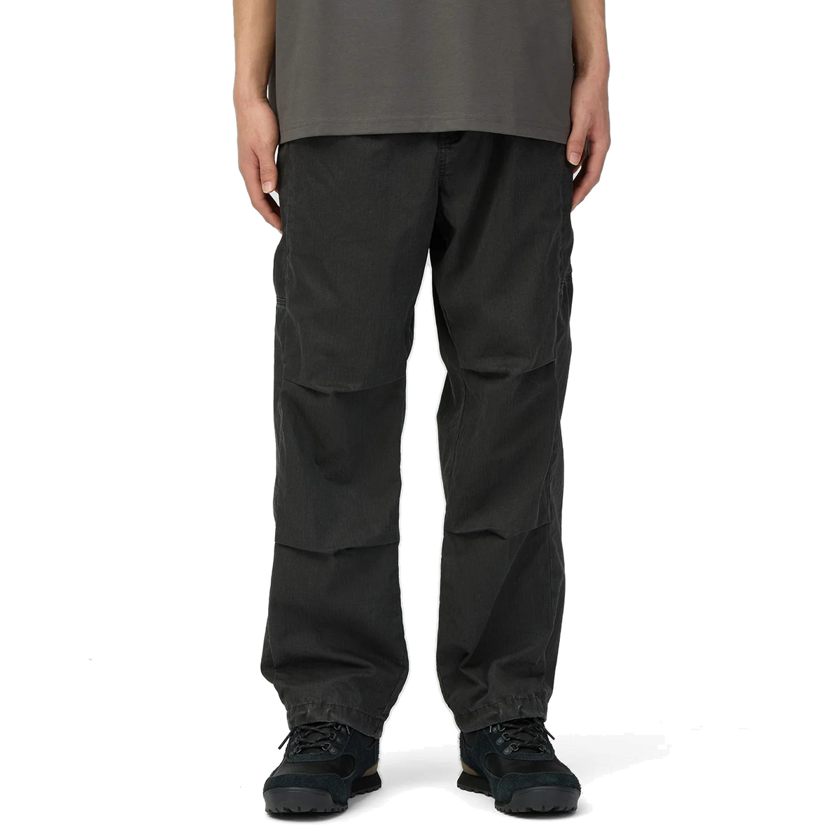 Model wearing charcoal Snow Peak Pigment Washed Pants with a grey T-shirt and black hiking shoes, showing the relaxed fit, darted knees and cinched drawcord hems.