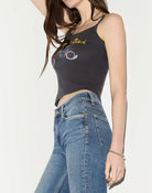 Woman wearing a black tank top and blue jeans on a white background