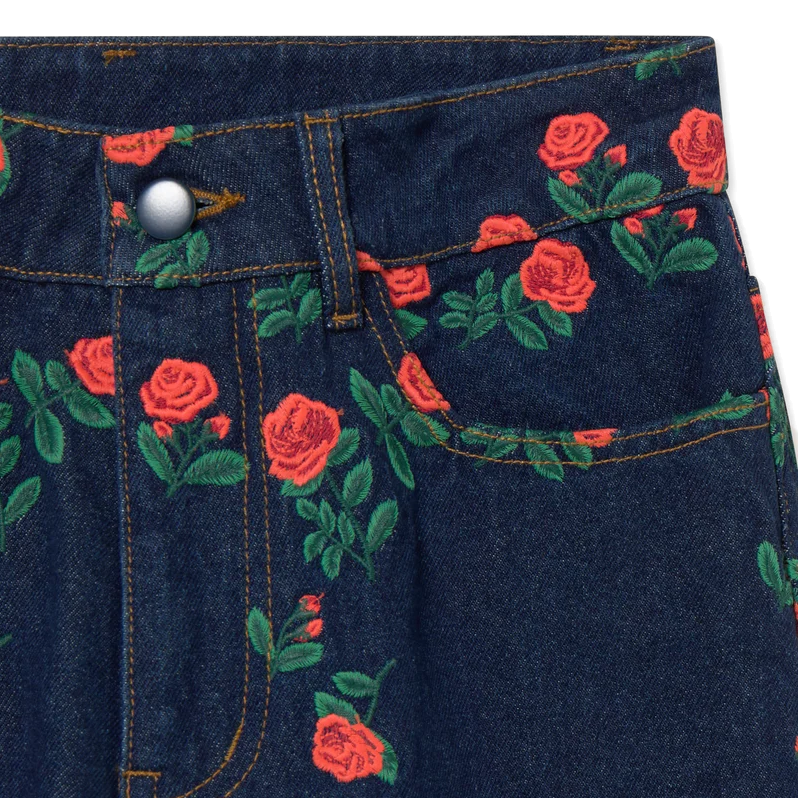 Close-up of the front waistband on The Tiny Big Sister Berta Long Jeans, showing the embroidered red roses and green leaves, silver shank button and contrast topstitching.
