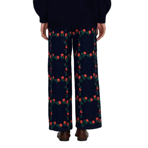 Back view of a model wearing The Tiny Big Sister Roses Grid Embroidery Berta Long Jeans with a navy knit sweater and brown loafers, showing the rose embroidery on the back.