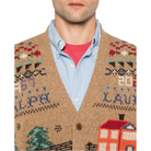Close-up of the Scenic Wool Cardigan’s V-neck, showing the “1967 Ralph” and “2026 Lauren” lettering, Fair Isle details and the knit farmhouse, worn over a light blue shirt.
