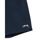 Close-up of the navy Sport Short’s leg, showing the cream Stüssy script logo and the split side hem.