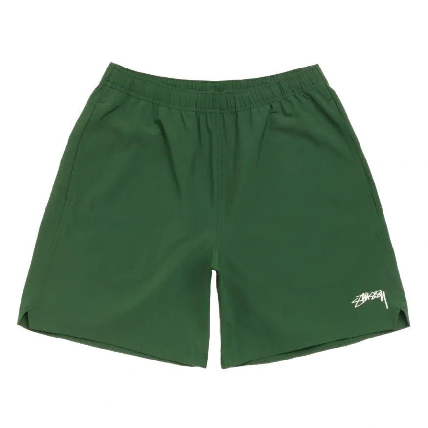 Front view of the Stüssy Sport Short in pine laid flat. Dark green shorts with an elastic waist, split side hems and a cream Stüssy script logo on the leg.