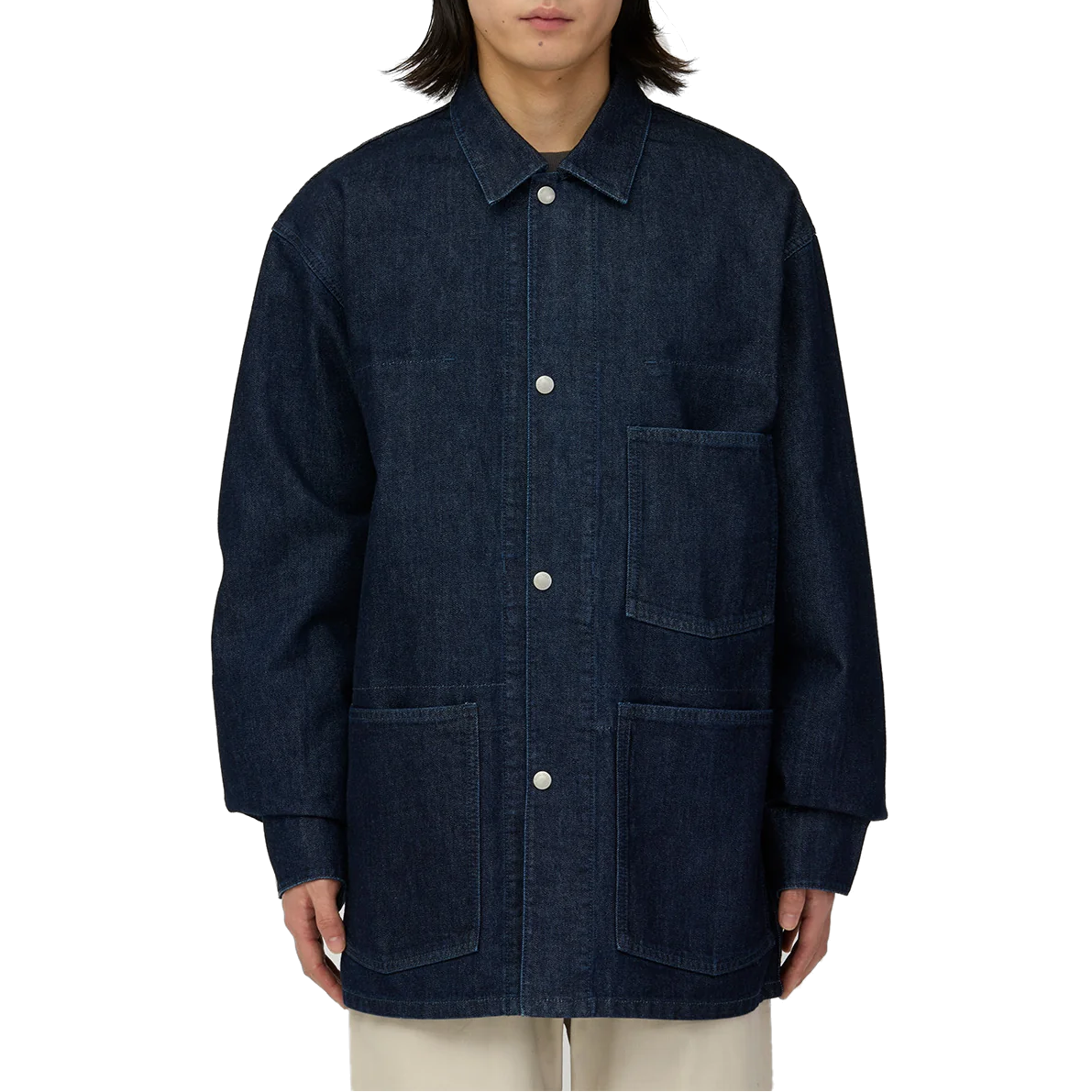 Model wearing an oversized Snow Peak Takibi Denim Jacket in dark indigo, buttoned with silver snaps, over light beige pants. Patch pockets sit on the chest and hips.